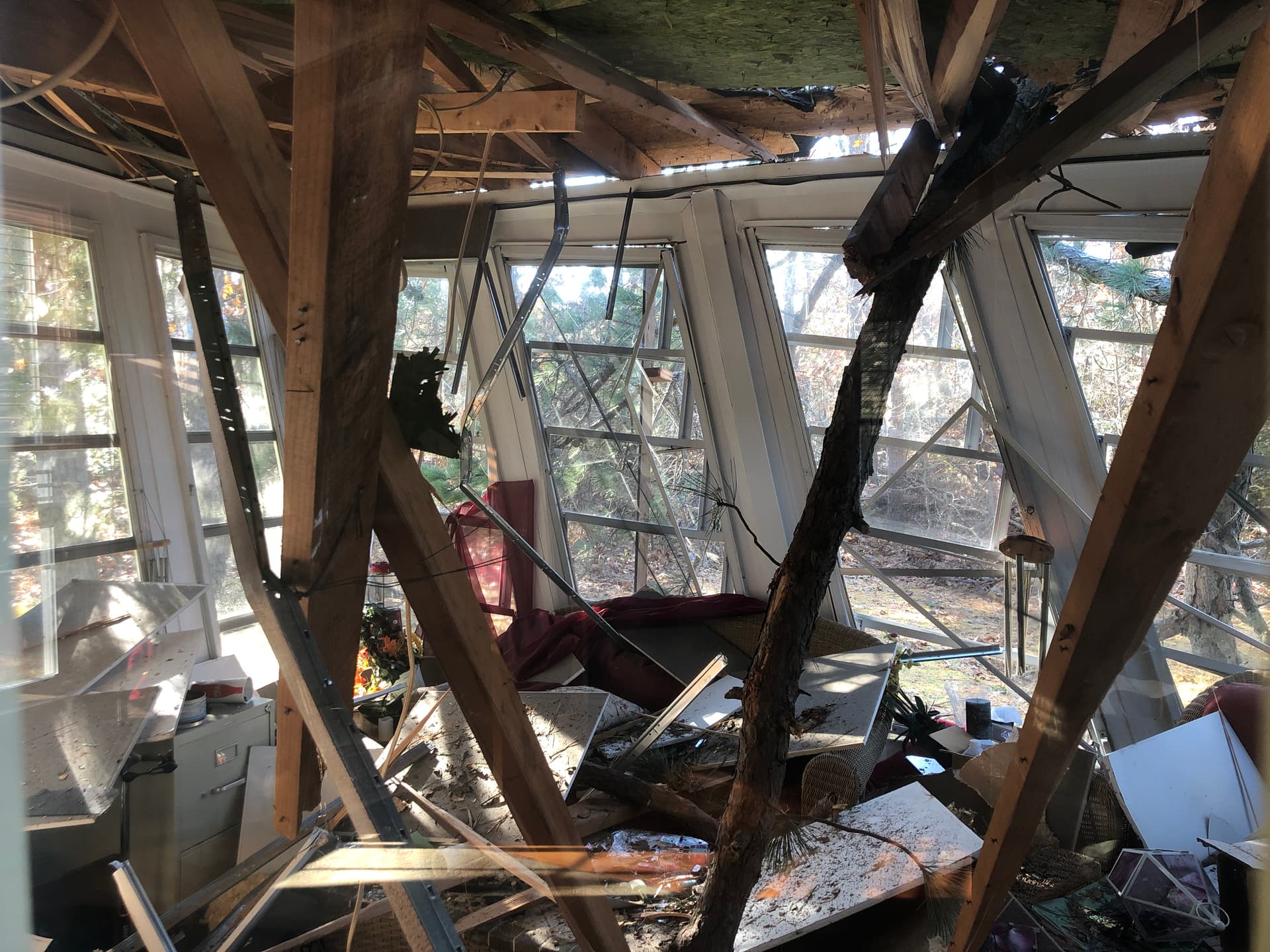 Fallen tree through an attached sunroom structure.